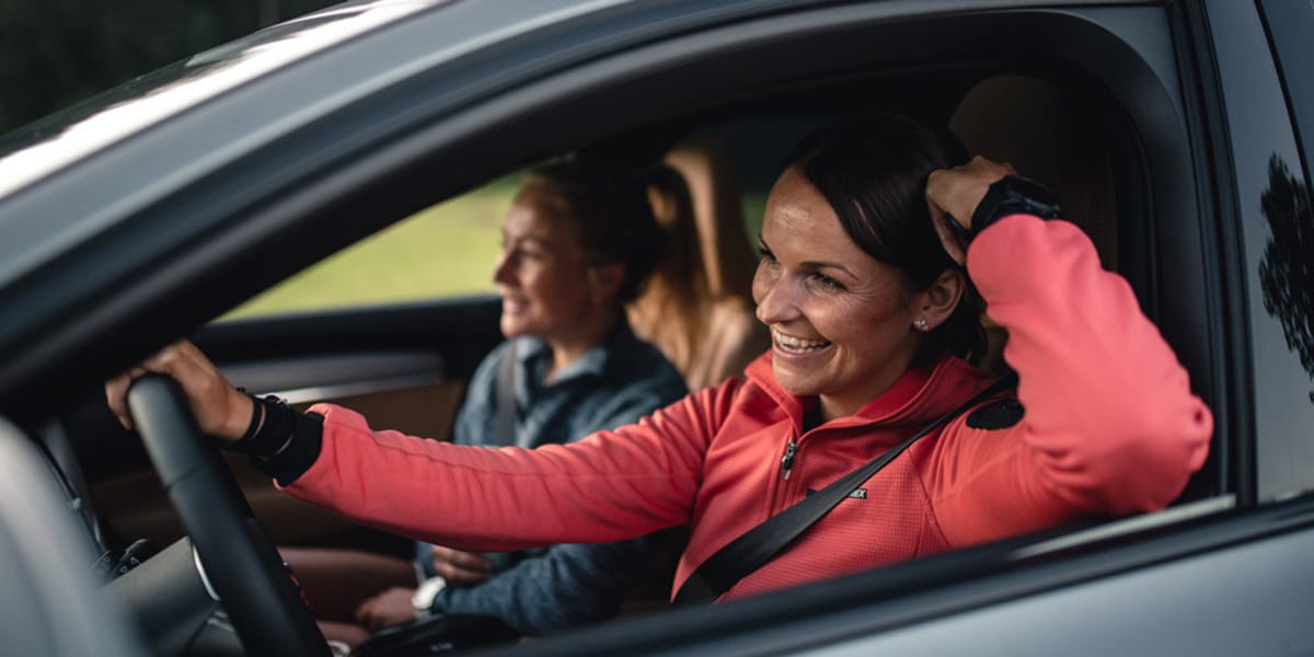 zwei Frauen fahren lachend im Auto