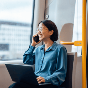 Frau nutzt Handy und Laptop auf dem Weg zur Arbeit in Deutscher Bahn