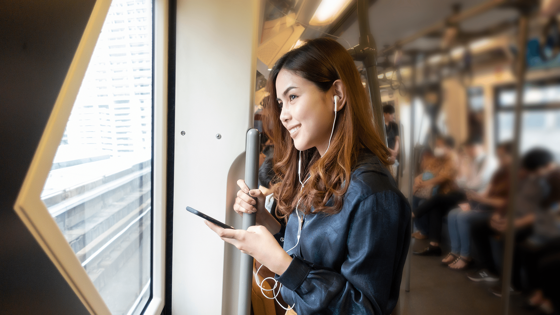 Frau auf einem Business Trip hält MOBIKO Business App in der Hand während sie in der Bahn steht