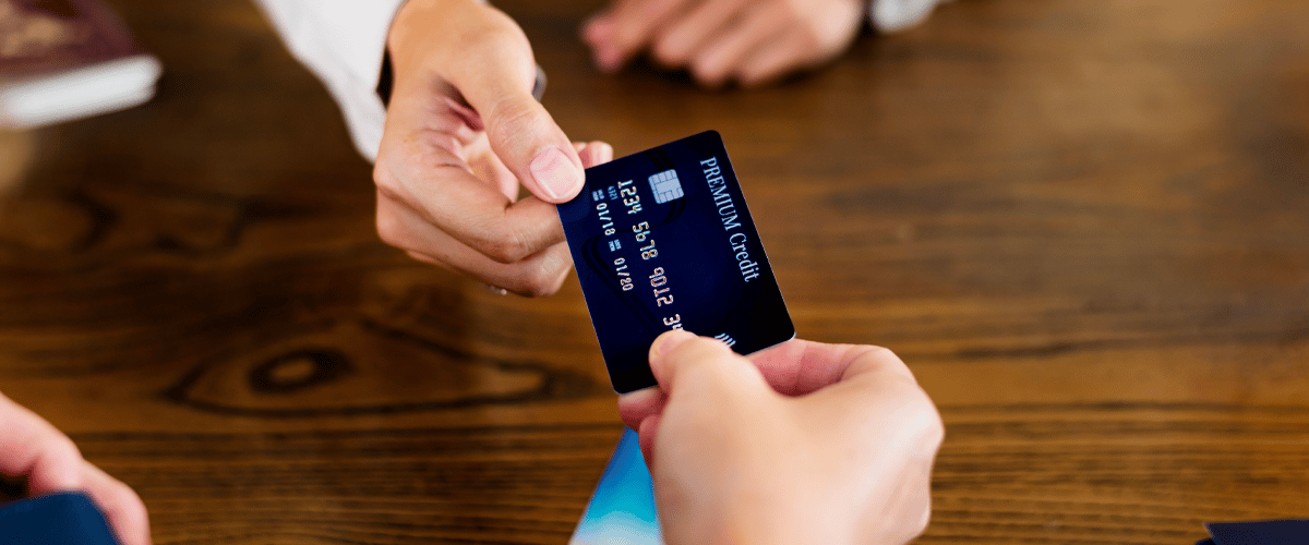 Eine weibliche Hand übergibt die Firmenkreditkarte.