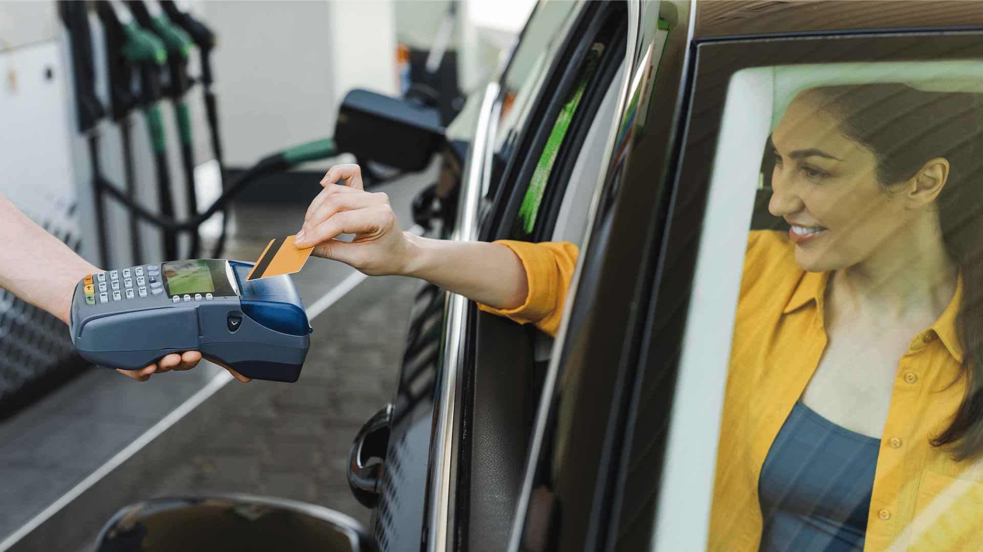 Eine junge Frau bezahlt nach dem Tanken per Tankkarte.