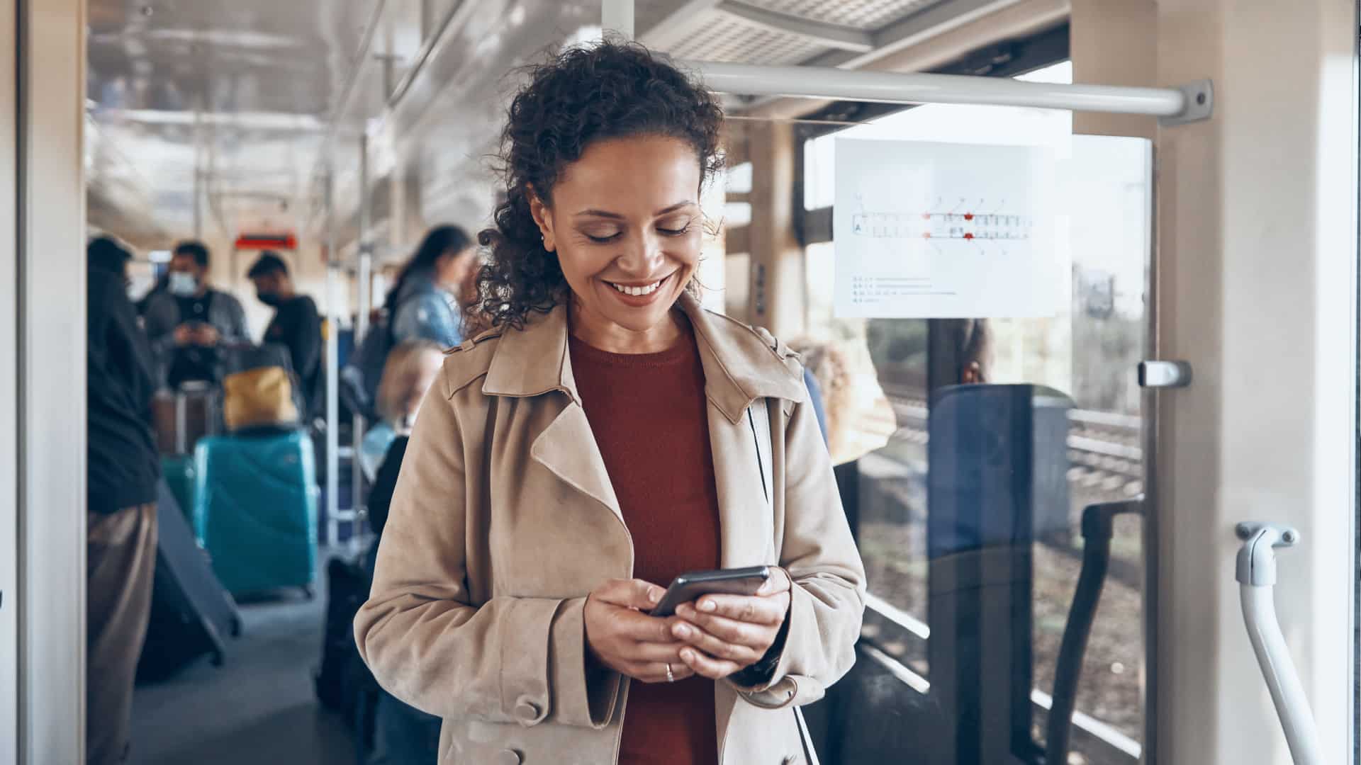 Frau in Bus, die lächelnd auf ihr Handy schaut