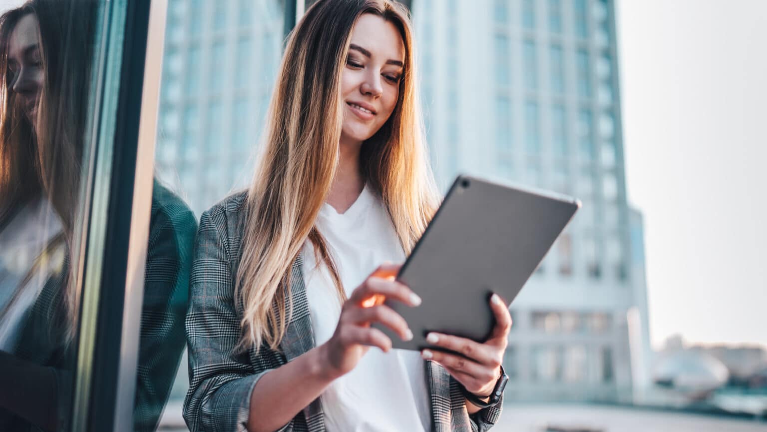Junge Frau in Blazer schaut auf Tablet
