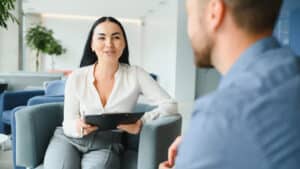 Mann und Frau sitzen einander gegenüber und erhalten sich geschäftlich