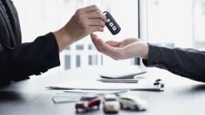 Person überreicht anderer Person einen Autoschlüssel