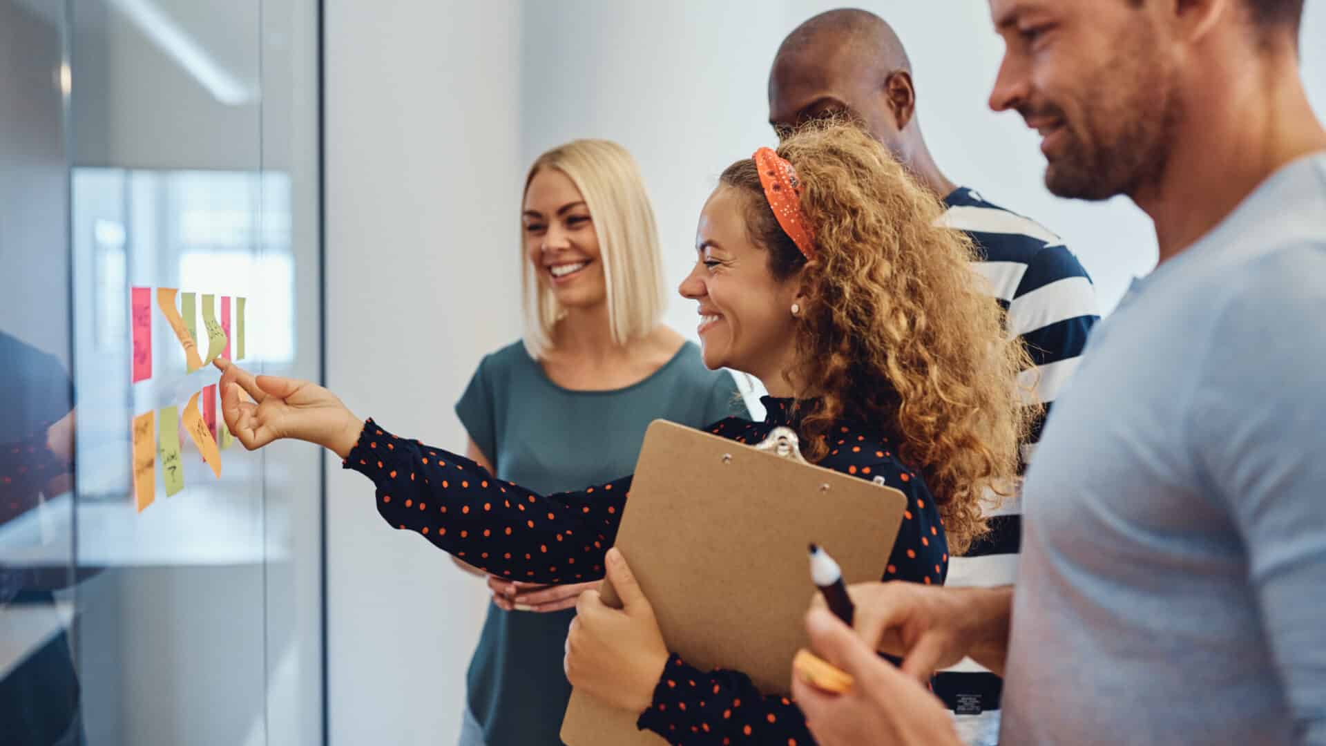 Vier glückliche Erwachsene stehen vor einem Flipchart